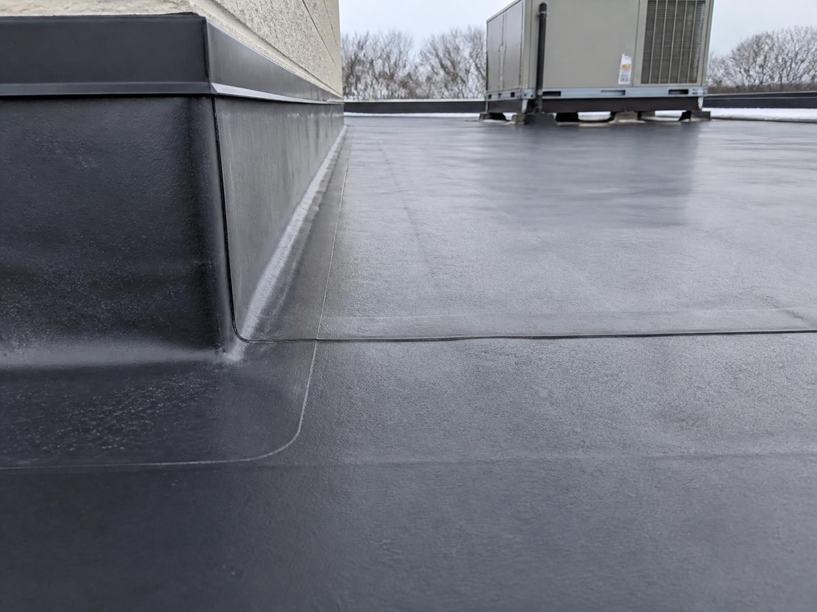 Black EPDM rubber membrane roof with perimeter flashing in winter light