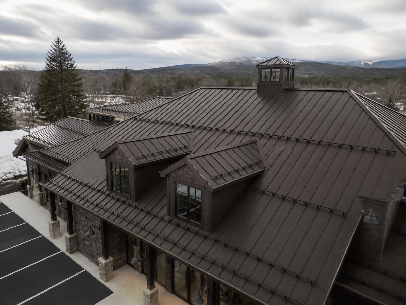 Dark bronze commercial standing seam metal roof with snow retention rails